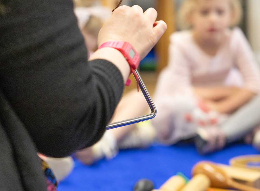 teacher with musical triangle in nursery
