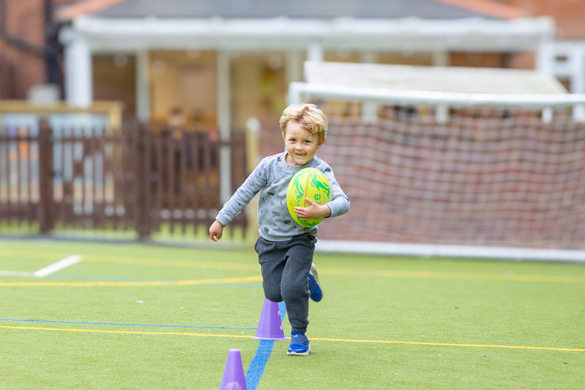 young boy runs with rugby ball